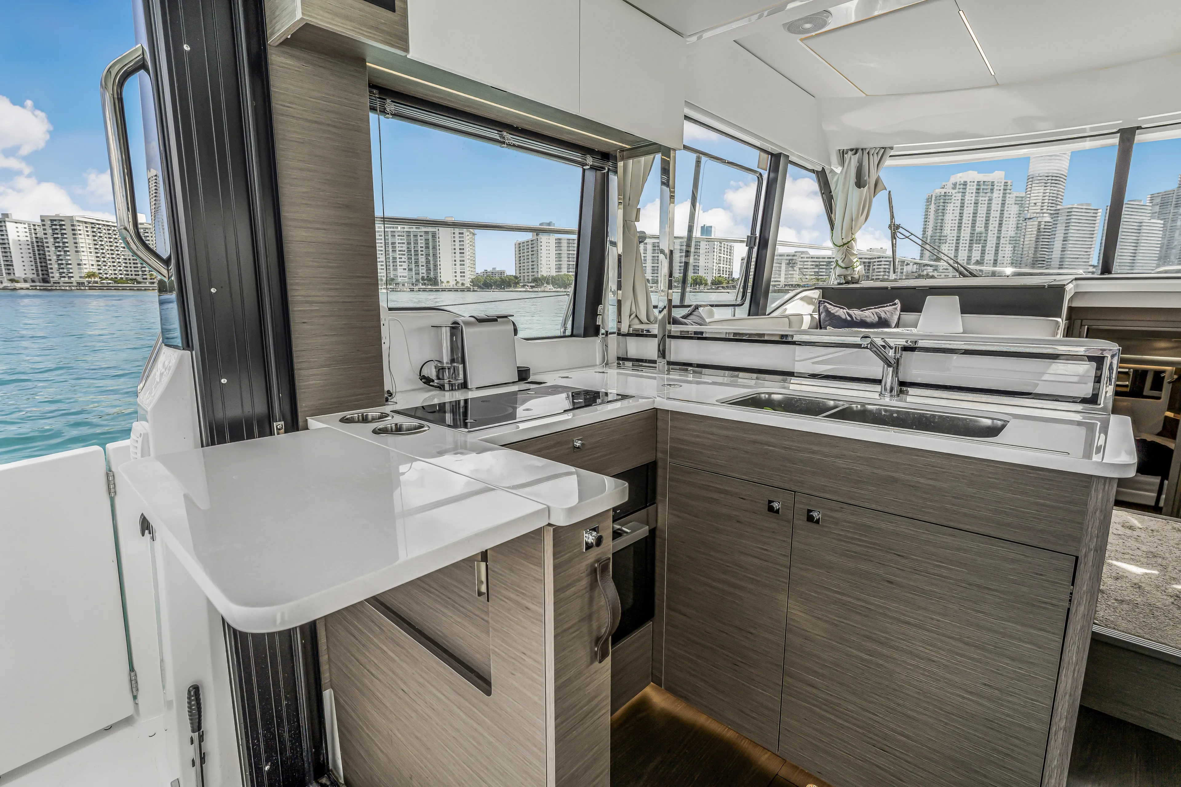 Rhapsody In Sea Yacht Photos Pics Modern kitchen interior on 2025 Jeanneau NC 1295 Fly yacht with cityscape view.