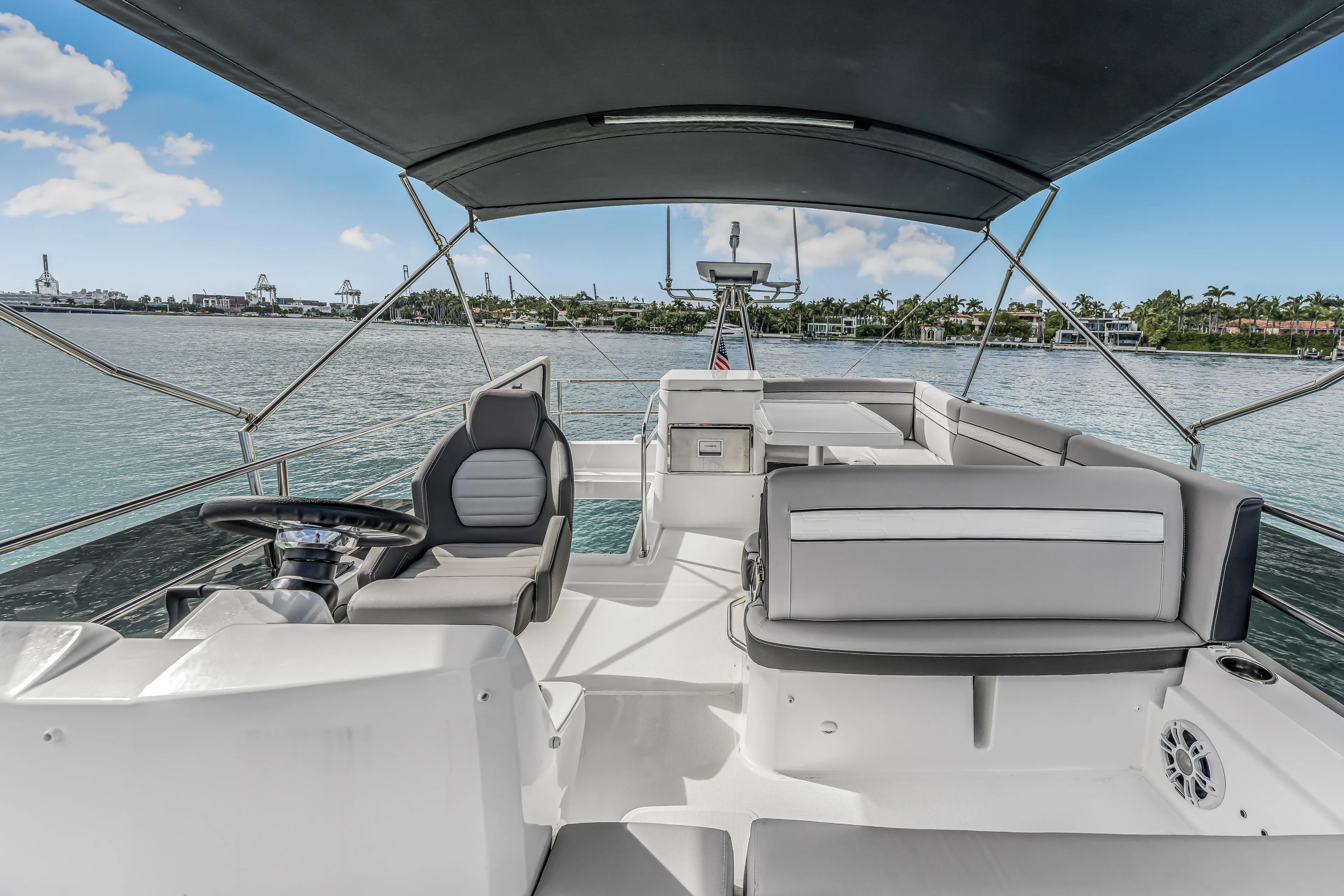 Rhapsody In Sea Yacht Photos Pics 2025 Jeanneau NC 1295 Flybridge with modern seating and scenic waterfront view.