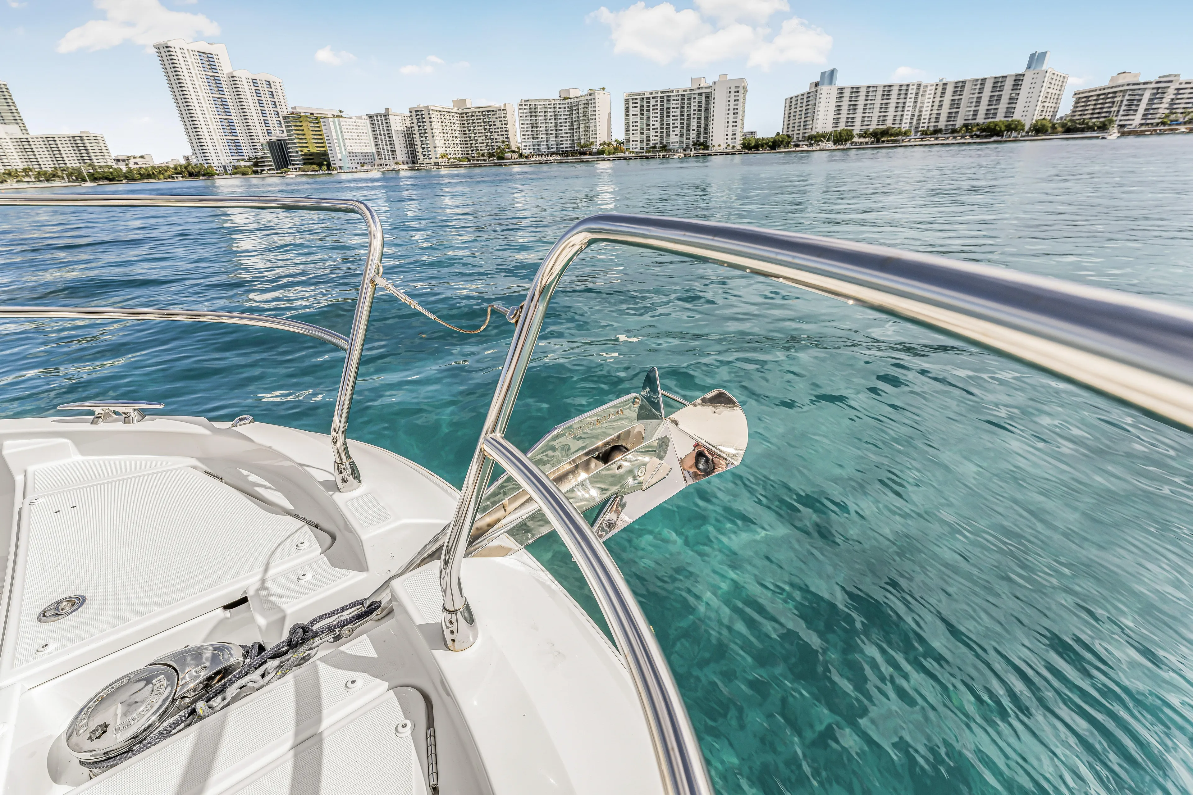 Rhapsody In Sea Yacht Photos Pics 2025 Jeanneau NC 1295 Fly yacht on clear water with city skyline backdrop.