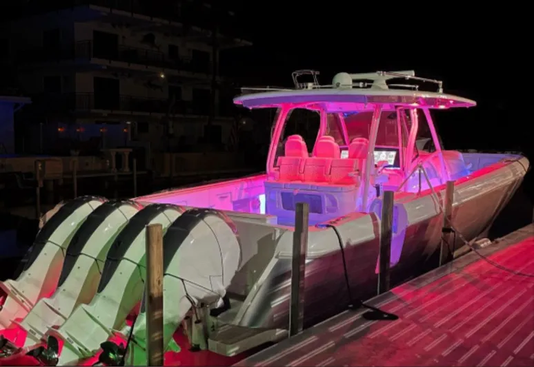Panacea Yacht Photos Pics 2019 Intrepid 475 Panacea boat illuminated with vibrant pink and purple lights at night.