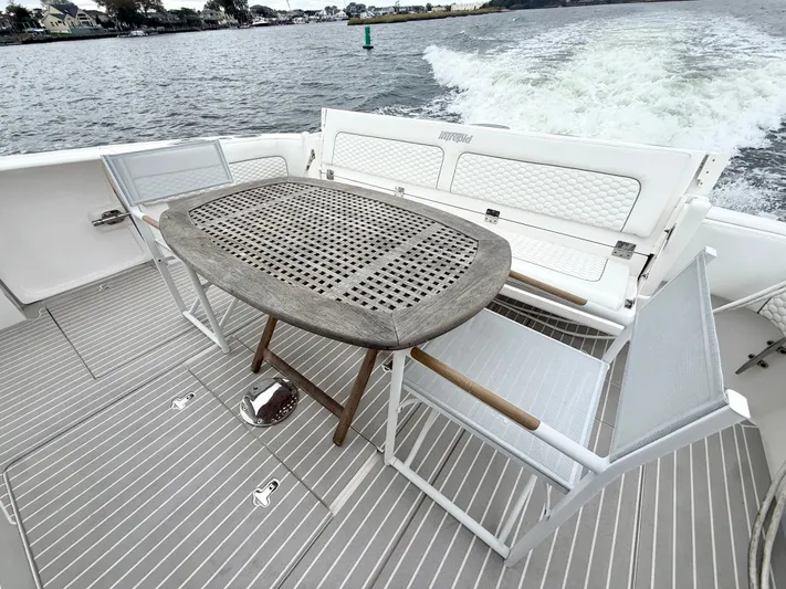 Panacea Yacht Photos Pics 2019 Intrepid 475 Panacea boat deck with table and chairs, cruising on water.