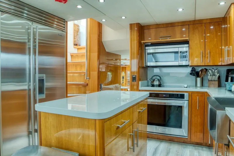 Majestik Yacht Photos Pics Luxurious kitchen in 2007 Hatteras 80 Enclosed Bridge yacht with modern appliances and wood cabinetry.