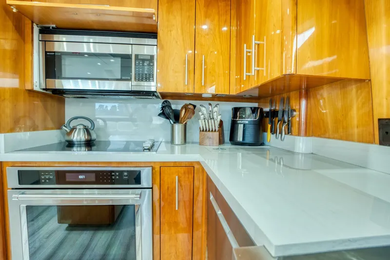 Majestik Yacht Photos Pics Modern kitchen in 2007 Hatteras 80 Enclosed Bridge yacht with wooden cabinets and stainless steel appliances.