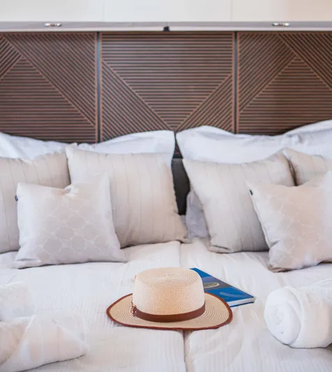  Yacht Photos Pics Luxurious bed with pillows, hat, and book on Prestige M48 yacht, 2024 model.