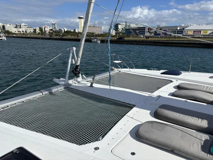 Adventure For Seven Yacht Photos Pics 2017 Fountaine Pajot Ipanema 58 catamaran with netted deck and cushioned seating, docked in a marina.