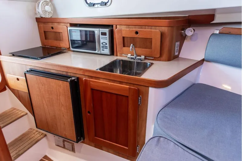 Battendown Yacht Photos Pics Compact kitchen area in a 2007 Hunt Surfhunter 29 boat with wooden cabinetry.