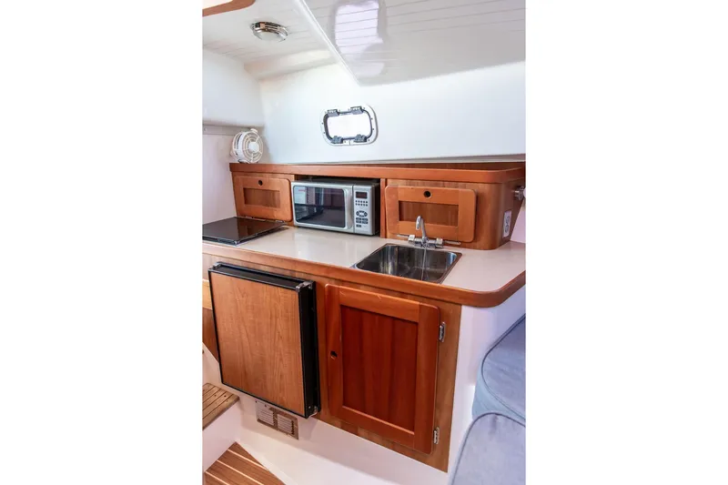 Battendown Yacht Photos Pics Compact kitchen in 2007 Hunt Surfhunter 29 boat with wood cabinetry and modern appliances.