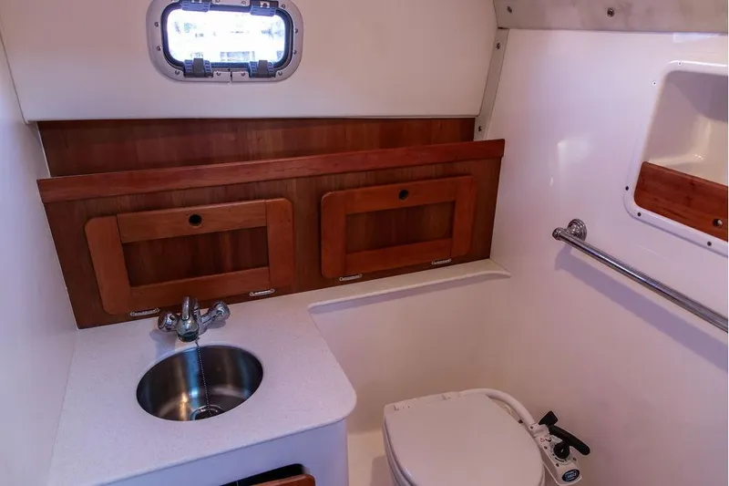 Battendown Yacht Photos Pics 2007 Hunt Surfhunter 29 boat bathroom with sink, toilet, and wooden cabinetry.