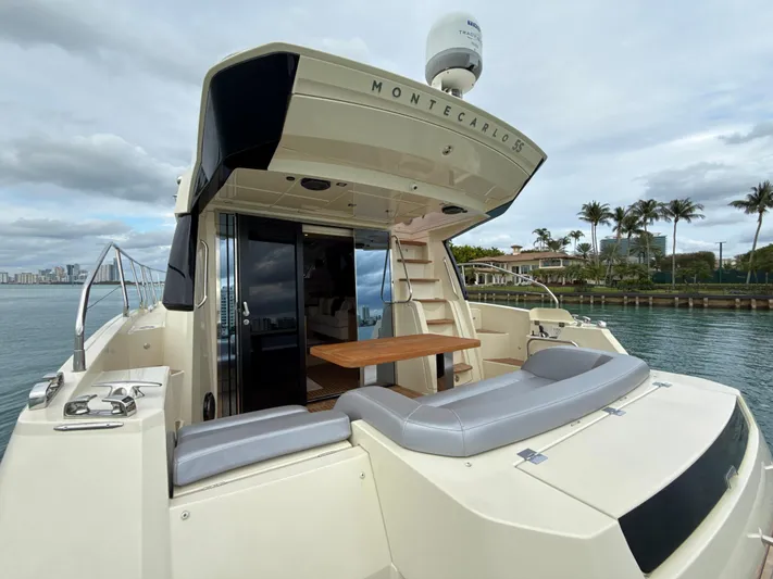  Yacht Photos Pics 2017 Beneteau Monte Carlo 5S yacht, rear view, docked by palm trees and water.
