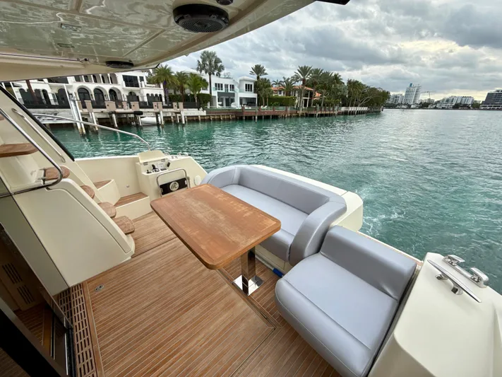  Yacht Photos Pics 2017 Beneteau Monte Carlo 5S yacht deck with seating and table, overlooking waterfront homes.