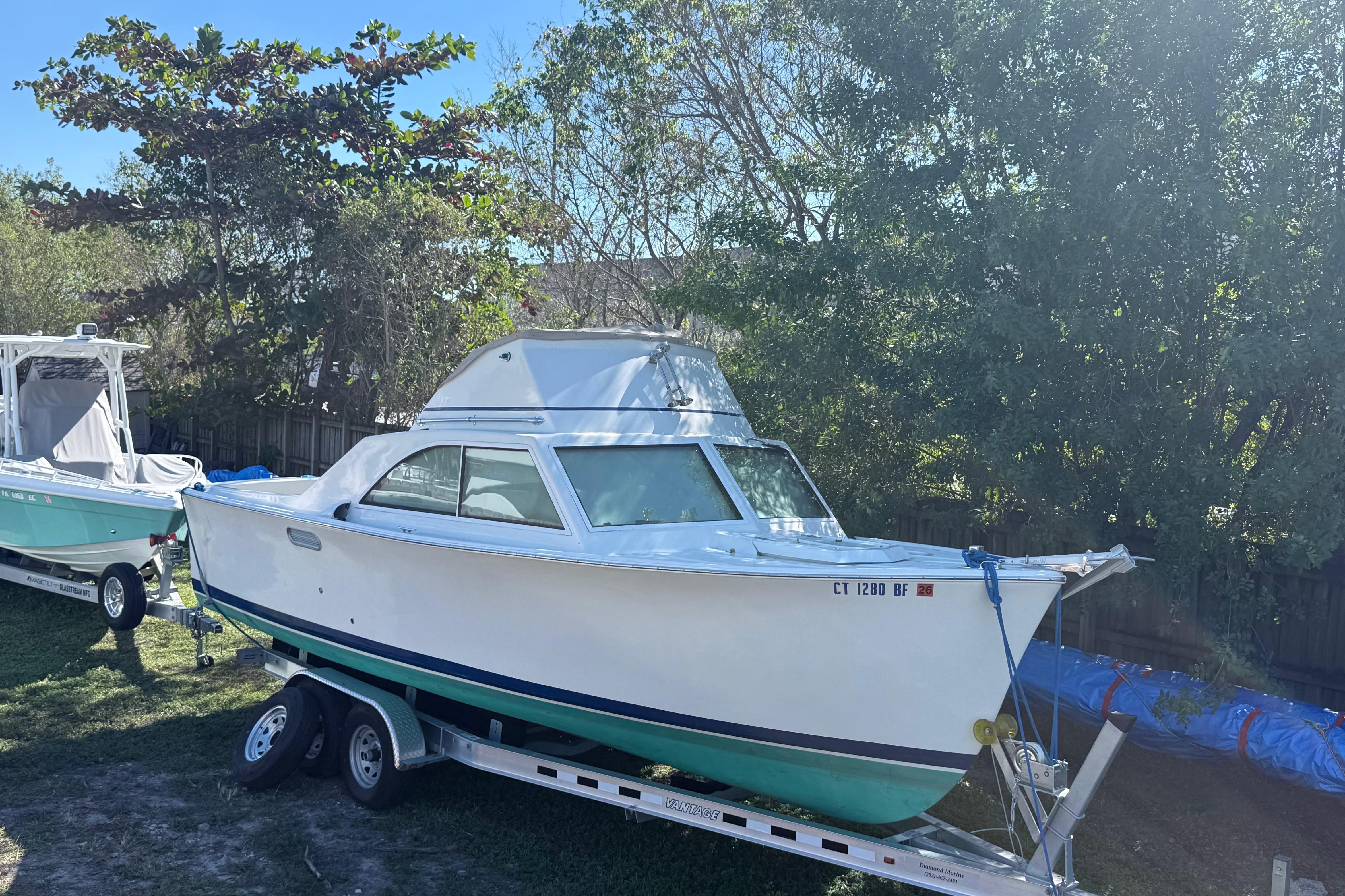 1969 Custom Alglas Saint John 25 ft. Sportfisher on trailer, surrounded by trees.