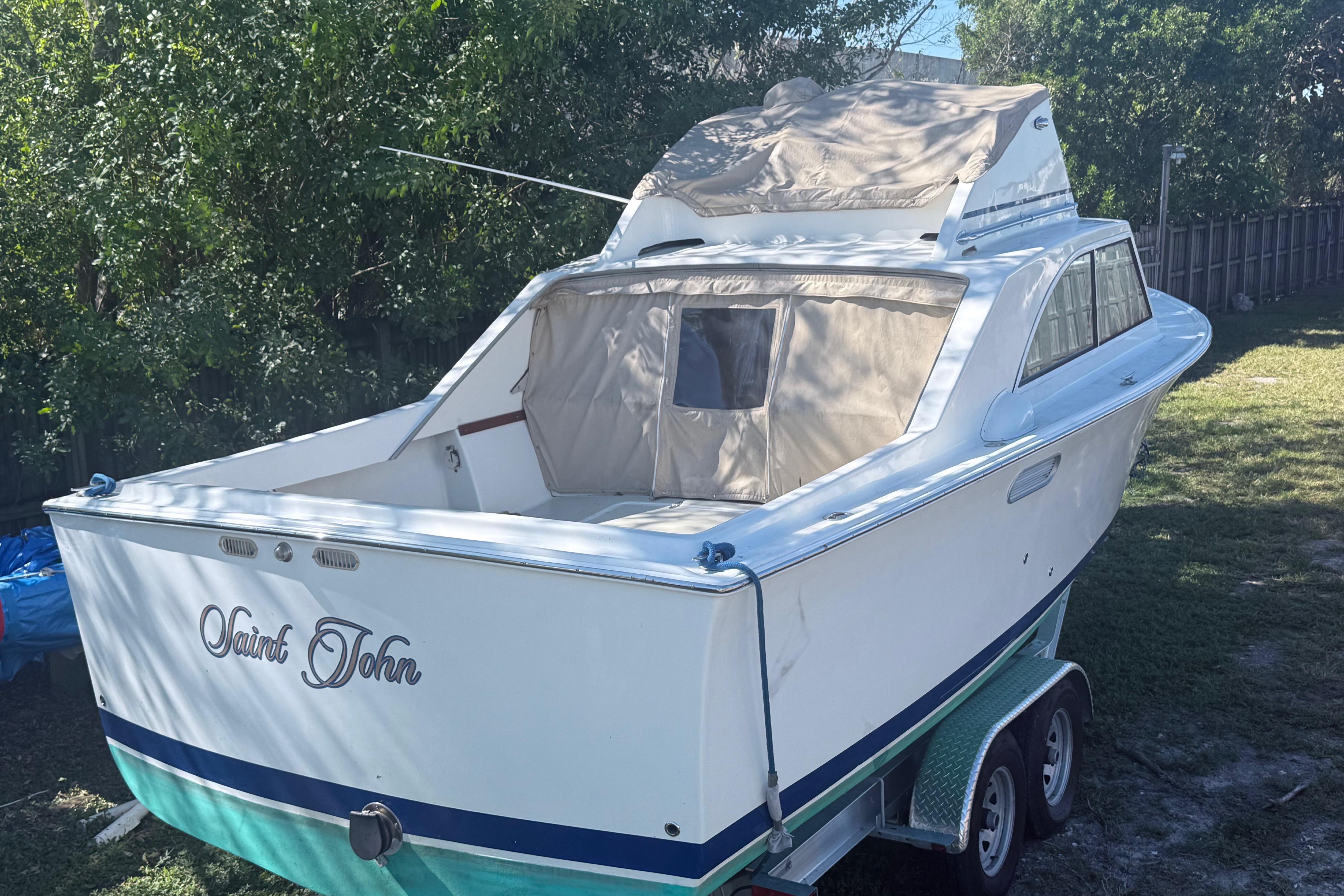 1969 Custom Alglas Saint John 25 ft. Sportfisher on trailer, surrounded by trees.