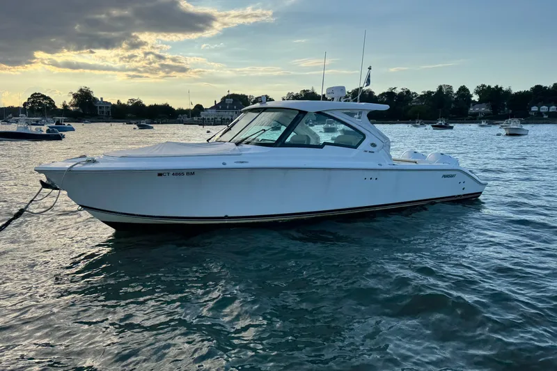  Yacht Photos Pics 2021 Pursuit DC 326 Dual Console boat on calm water at sunset.