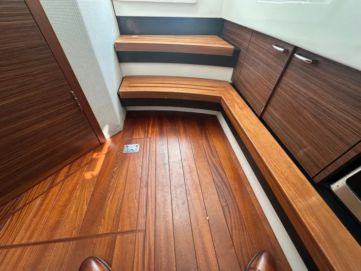  Yacht Photos Pics 2020 Pursuit S368 interior with wooden flooring and steps, featuring sleek cabinetry.