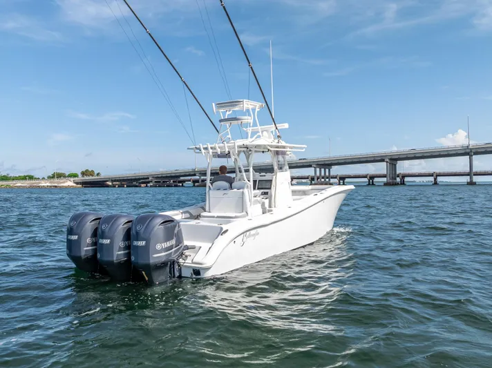  Yacht Photos Pics 2021 Yellowfin 34 boat with triple Yamaha engines on open water near a bridge.