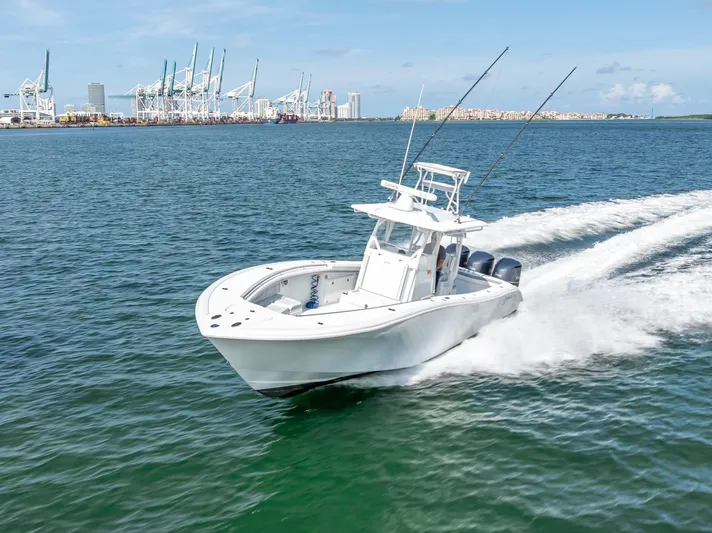  Yacht Photos Pics 2021 Yellowfin 34 boat cruising near a port with cranes in the background.