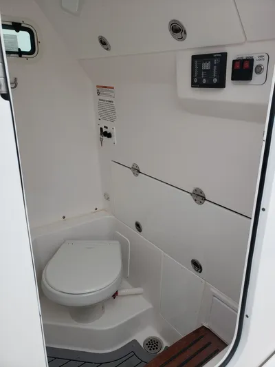  Yacht Photos Pics 2023 Everglades 285CC boat interior with compact marine toilet and control panel.