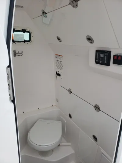  Yacht Photos Pics 2023 Everglades 285CC boat interior with compact marine toilet and control panel.