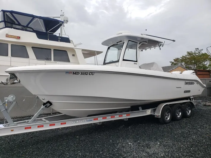  Yacht Photos Pics 2023 Everglades 285CC boat on trailer, parked beside another vessel.