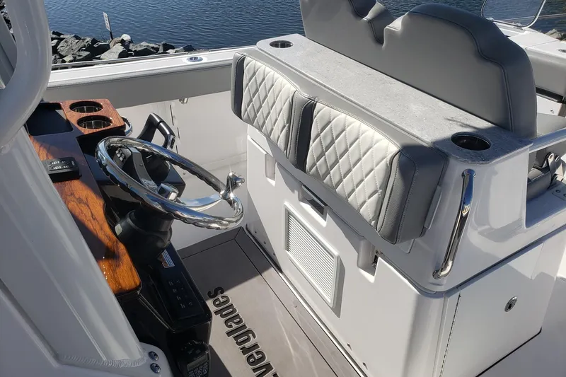  Yacht Photos Pics 2023 Everglades 285CC boat interior with steering wheel and cushioned seating.