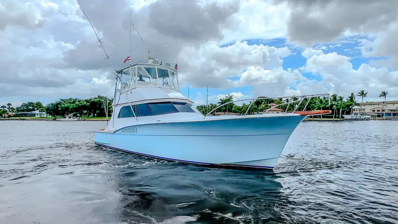 Julia G Yacht Photos Pics 1982 Hatteras 46 Convertible yacht on calm water under cloudy sky.