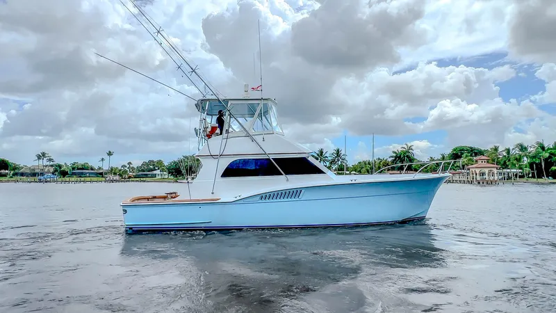 Julia G Yacht Photos Pics 1982 Hatteras 46 Convertible yacht on calm water under cloudy sky.