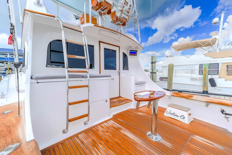 Julia G Yacht Photos Pics 1982 Hatteras 46 Convertible yacht with wooden deck and ladder, docked under blue sky.