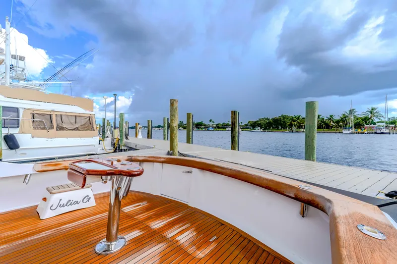 Julia G Yacht Photos Pics 1982 Hatteras 46 Convertible yacht docked, featuring a wooden deck and scenic waterfront view.