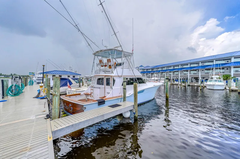 Julia G Yacht Photos Pics 1982 Hatteras 46 Convertible yacht docked at marina under cloudy sky.