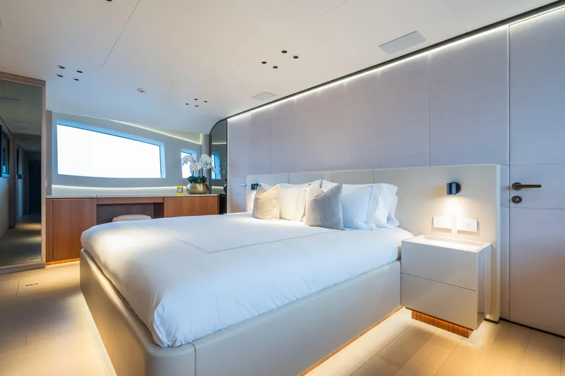  Yacht Photos Pics Luxurious bedroom interior of 2023 Mangusta 104 REV yacht, featuring modern design and ambient lighting.