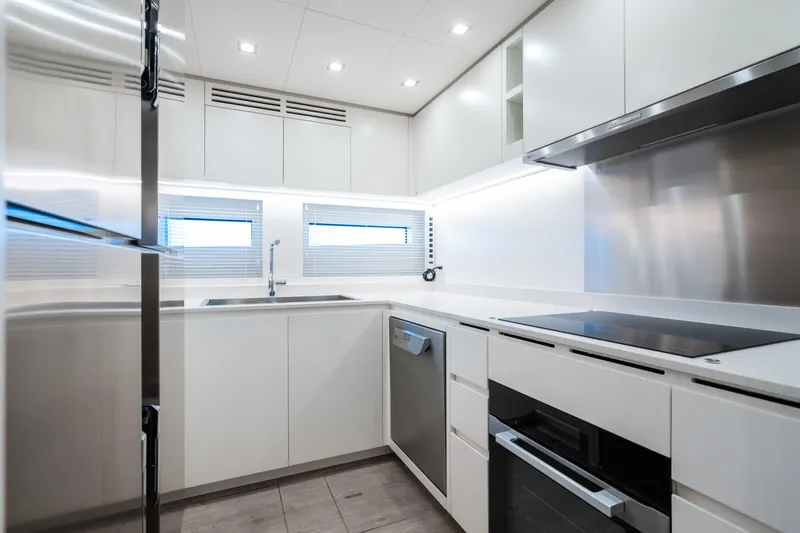  Yacht Photos Pics Modern kitchen interior in 2023 Mangusta 104 REV yacht, featuring sleek white cabinetry.