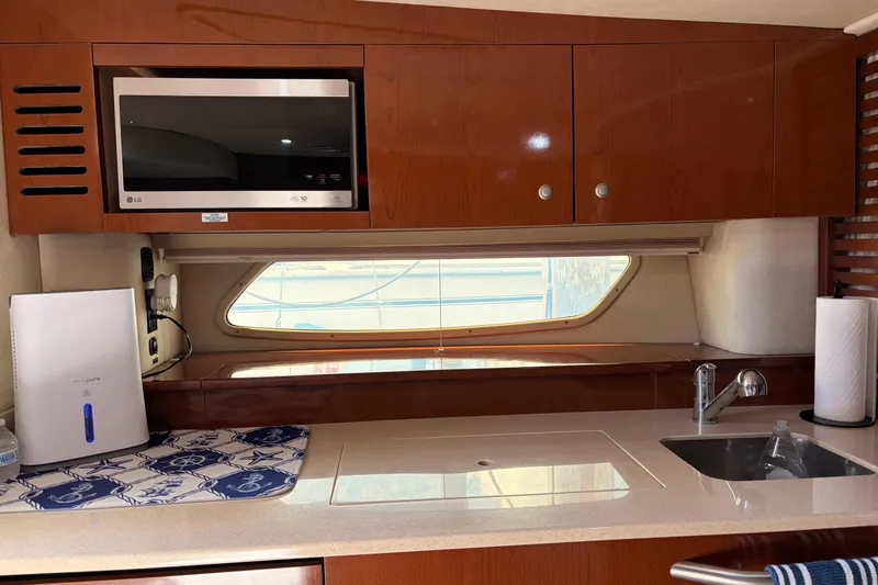  Yacht Photos Pics 2008 Sea Ray Sundancer 350 yacht kitchen with microwave, sink, and wooden cabinets.