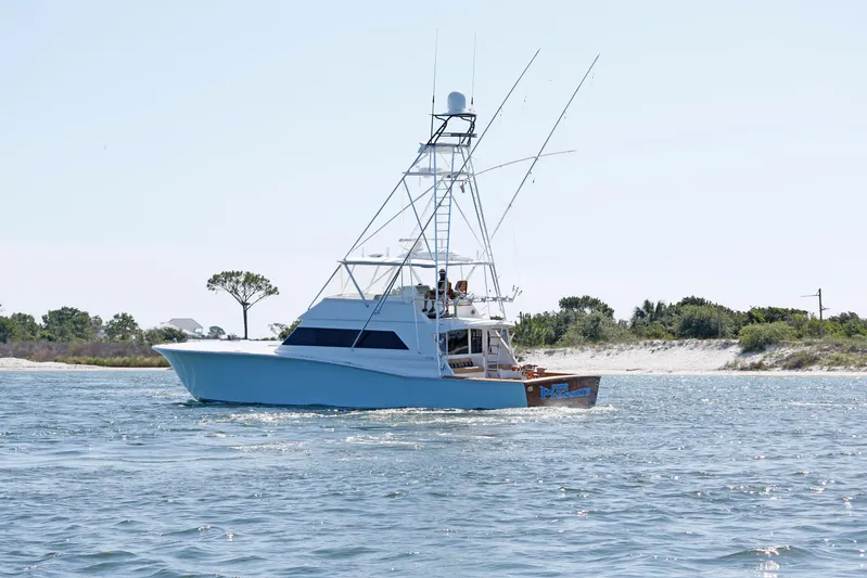 Pier Pressure Yacht Photos Pics A 2000 Jim Smith 65 Convertible yacht cruising near a sandy shoreline.