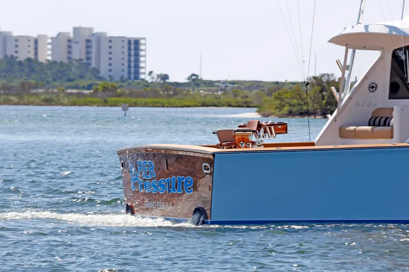 Pier Pressure Yacht Photos Pics Jim Smith 65 Convertible boat cruising near shoreline with buildings in the background.
