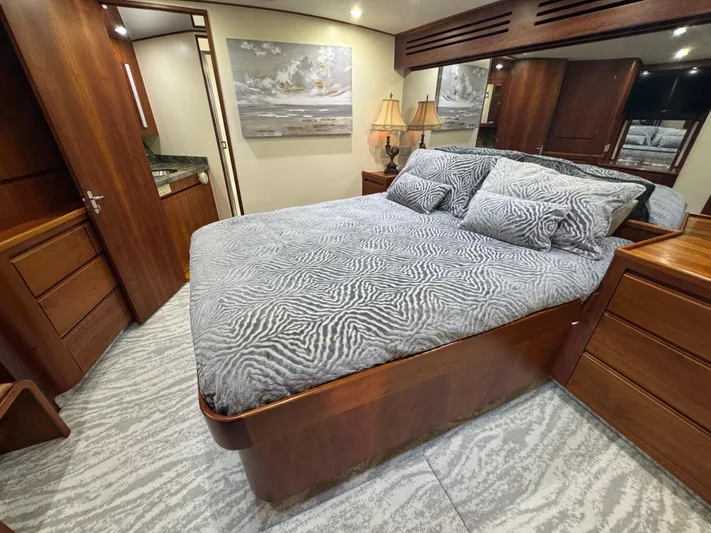 Pier Pressure Yacht Photos Pics Luxurious bedroom interior of a 2000 Jim Smith 65 Convertible yacht, featuring elegant wood finishes.