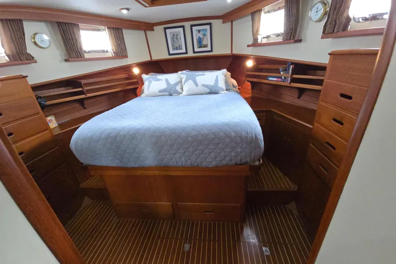 Halcyon Yacht Photos Pics Luxurious cabin interior of 2005 Grand Banks 46 Europa yacht with cozy bed and wooden finish.