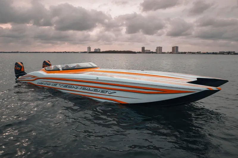  Yacht Photos Pics 2024 MTI 390X powerboat with sleek design on calm water under cloudy sky.
