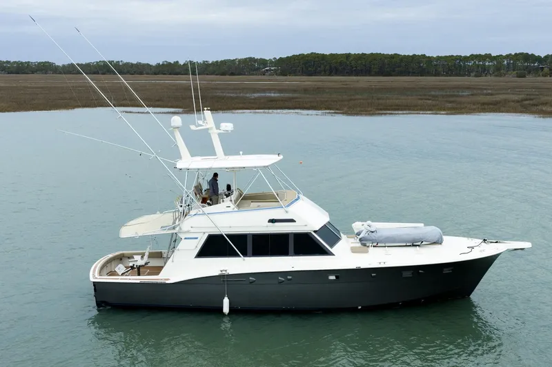  Yacht Photos Pics 1984 Hatteras 52 Convertible yacht on calm water, featuring a sleek design and fishing equipment.