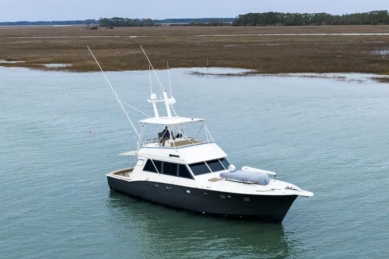  Yacht Photos Pics 1984 Hatteras 52 Convertible yacht on calm water, surrounded by marshland.