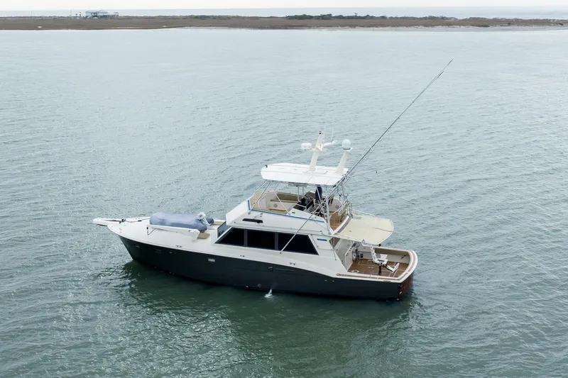  Yacht Photos Pics 1984 Hatteras 52 Convertible yacht on calm waters, distant shoreline visible.