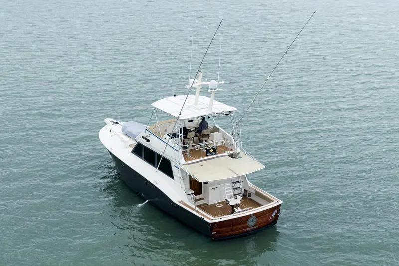  Yacht Photos Pics 1984 Hatteras 52 Convertible yacht on calm water, rear view with fishing rods.
