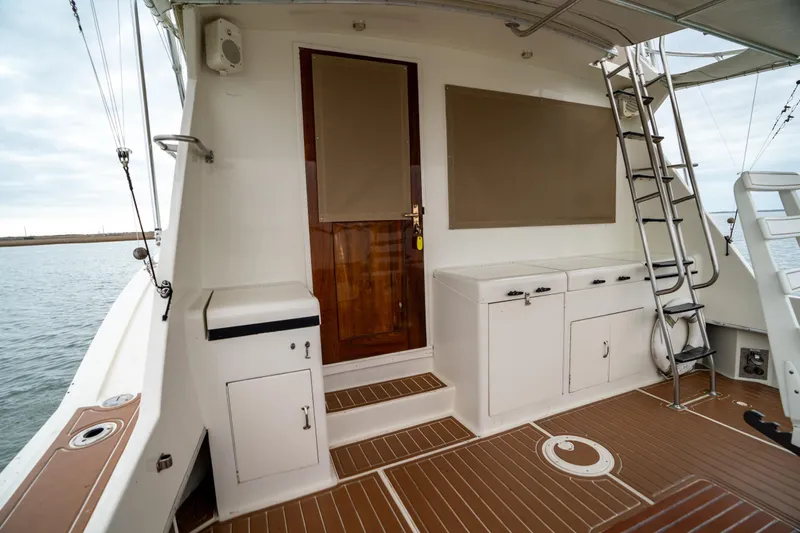  Yacht Photos Pics 1984 Hatteras 52 Convertible yacht deck with wooden door, storage cabinets, and ladder.