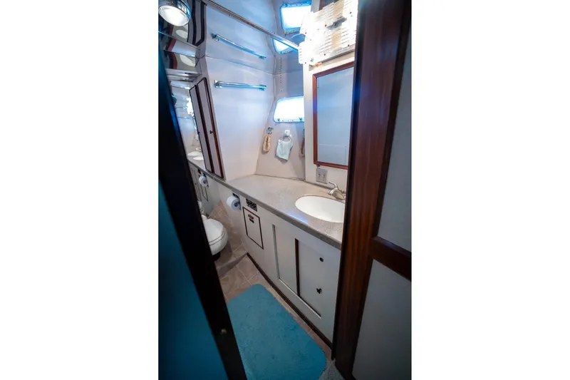  Yacht Photos Pics 1984 Hatteras 52 Convertible yacht bathroom with sink, mirror, and storage cabinets.