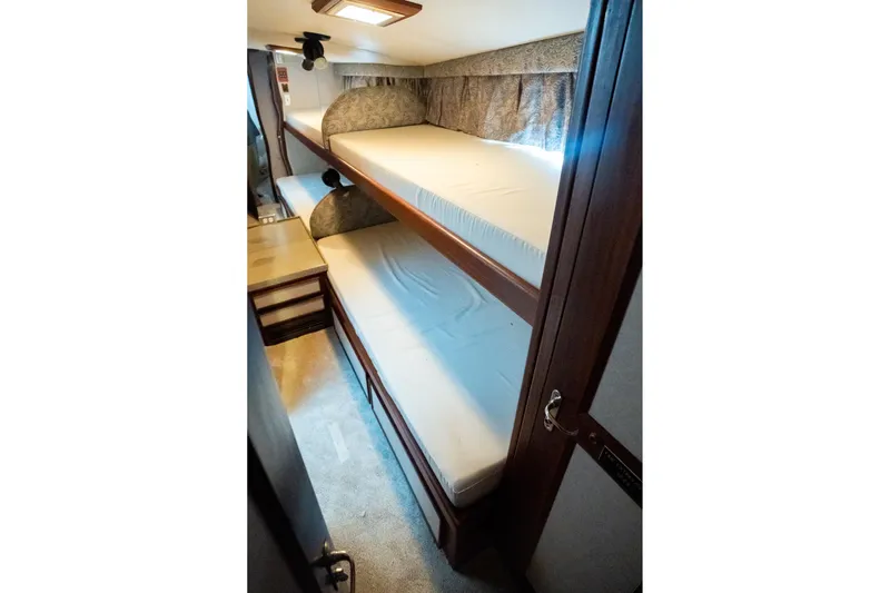  Yacht Photos Pics Bunk beds in 1984 Hatteras 52 Convertible yacht cabin, featuring wood accents and cozy lighting.