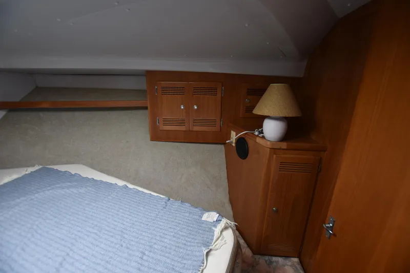 Yacht Photos Pics 1994 Cabo 35 Flybridge Sportfisher cabin interior with bed, wooden cabinets, and lamp.