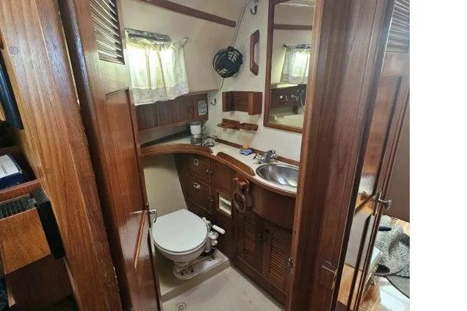 Water Dance Yacht Photos Pics 1999 Island Packet 350 yacht bathroom with wooden cabinetry, sink, and toilet.