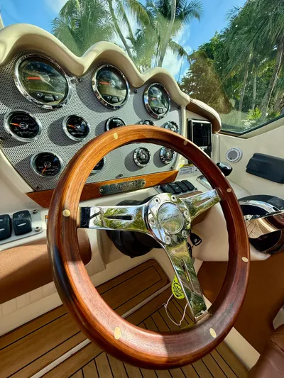  Yacht Photos Pics 2015 Chris-Craft Launch 32 dashboard with wooden steering wheel and gauges, surrounded by palm trees.