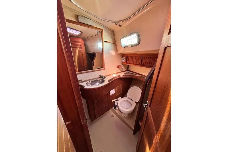 Butternut Yacht Photos Pics 1995 Island Packet 37 yacht bathroom with wooden cabinetry and stainless steel sink.