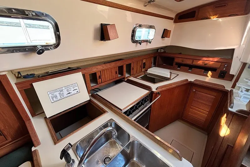 Butternut Yacht Photos Pics Interior of 1995 Island Packet 37 sailboat kitchen with wooden cabinetry and stainless steel sink.