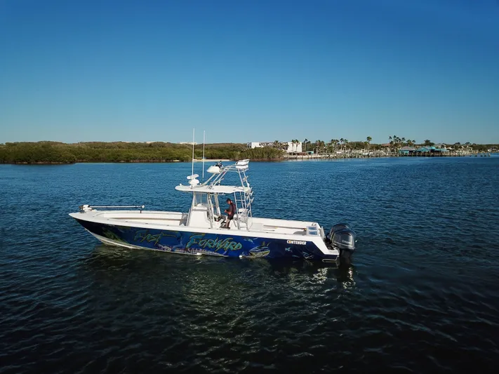 Fast Forward Yacht Photos Pics 2010 Contender 39 ST boat on calm water with scenic shoreline background.